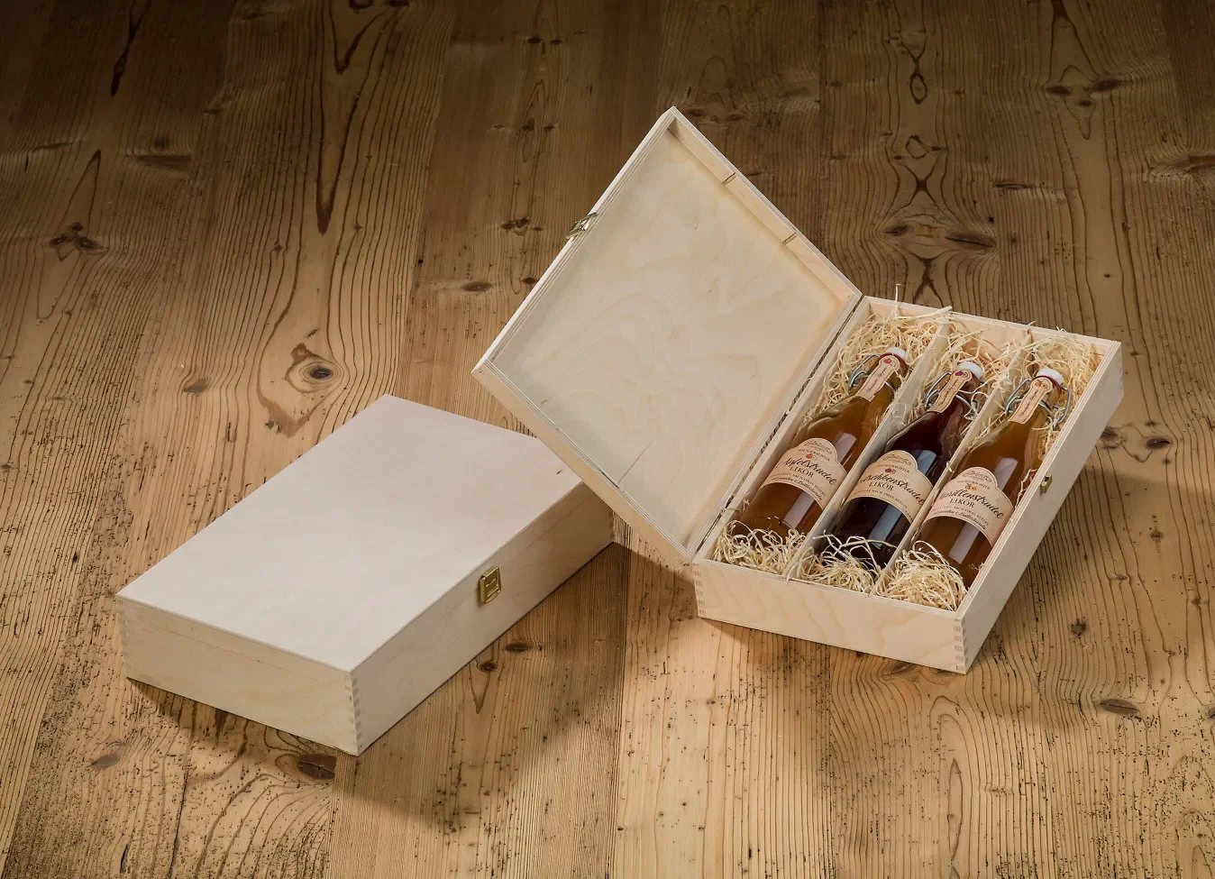 Standardkiste aus Holz gefüllt mit 3 Flaschen und Holzwolle auf einem alten Holzboden